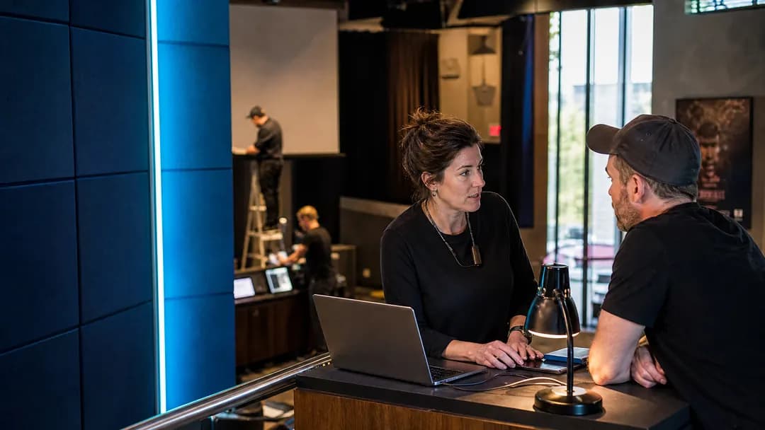 Manager and a colleague reviewing performance data on a laptop at a counter in a lit showroom space